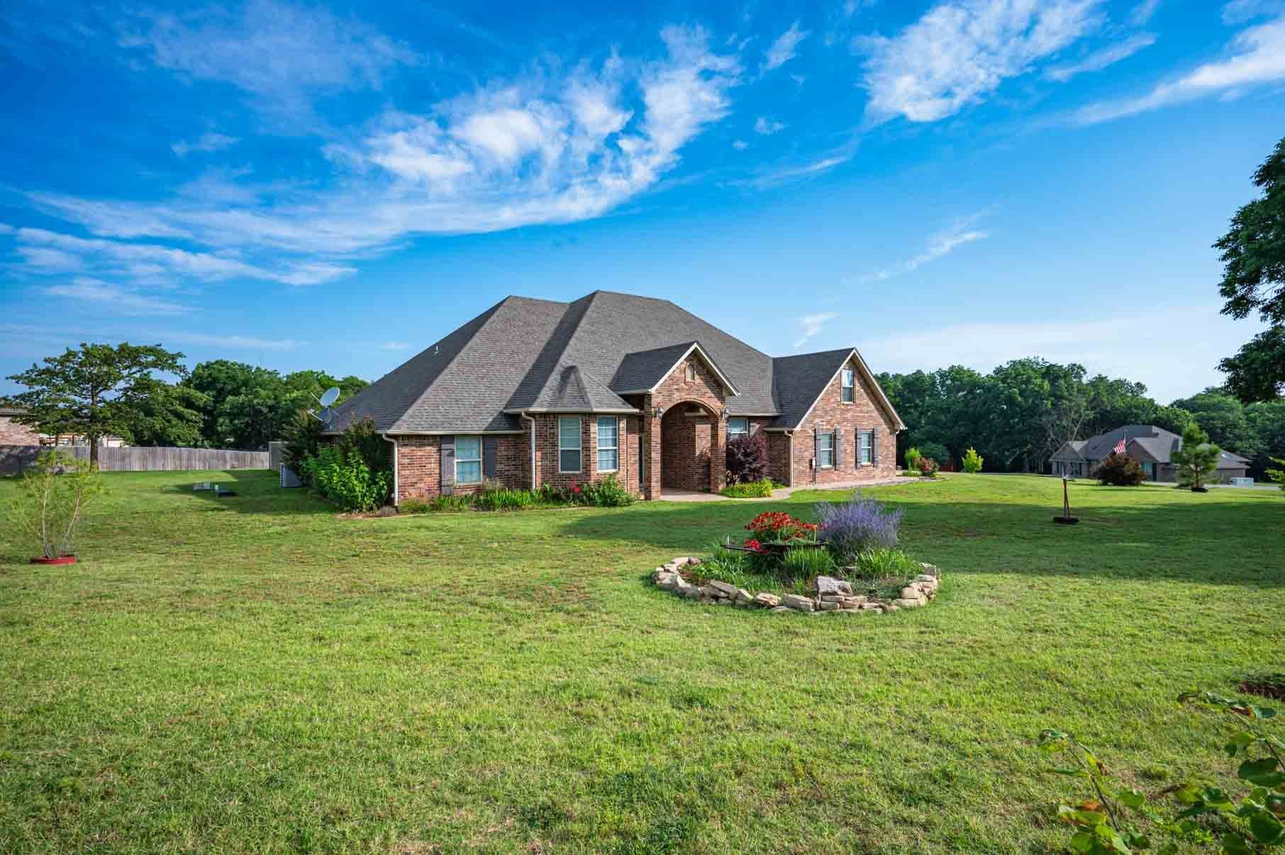 Brick home with an arched entry set back on a wide lawn