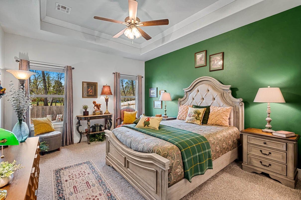 Bedroom with a deep green accent wall and an upholstered headboard