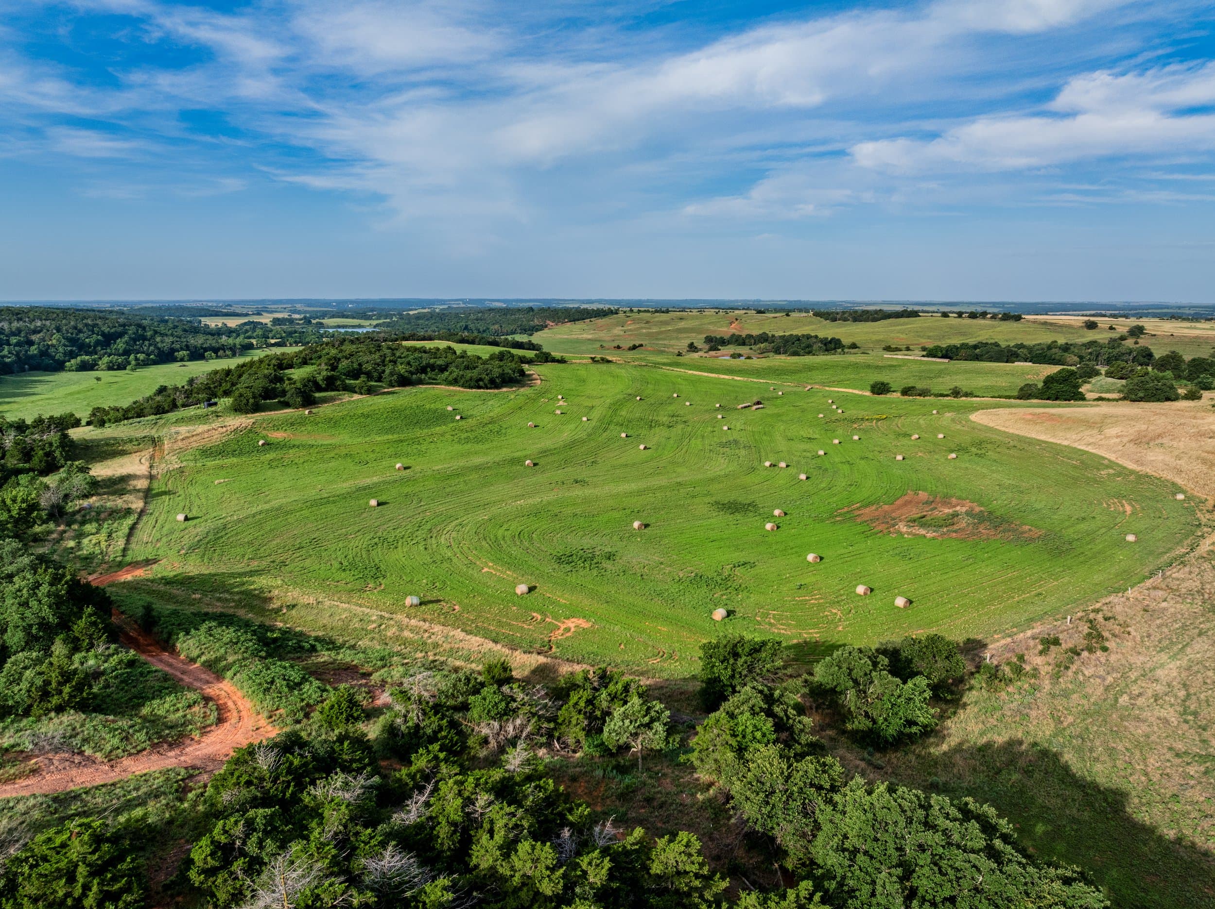 Aerial view of rolling hay meadows and treelines at the edge of town