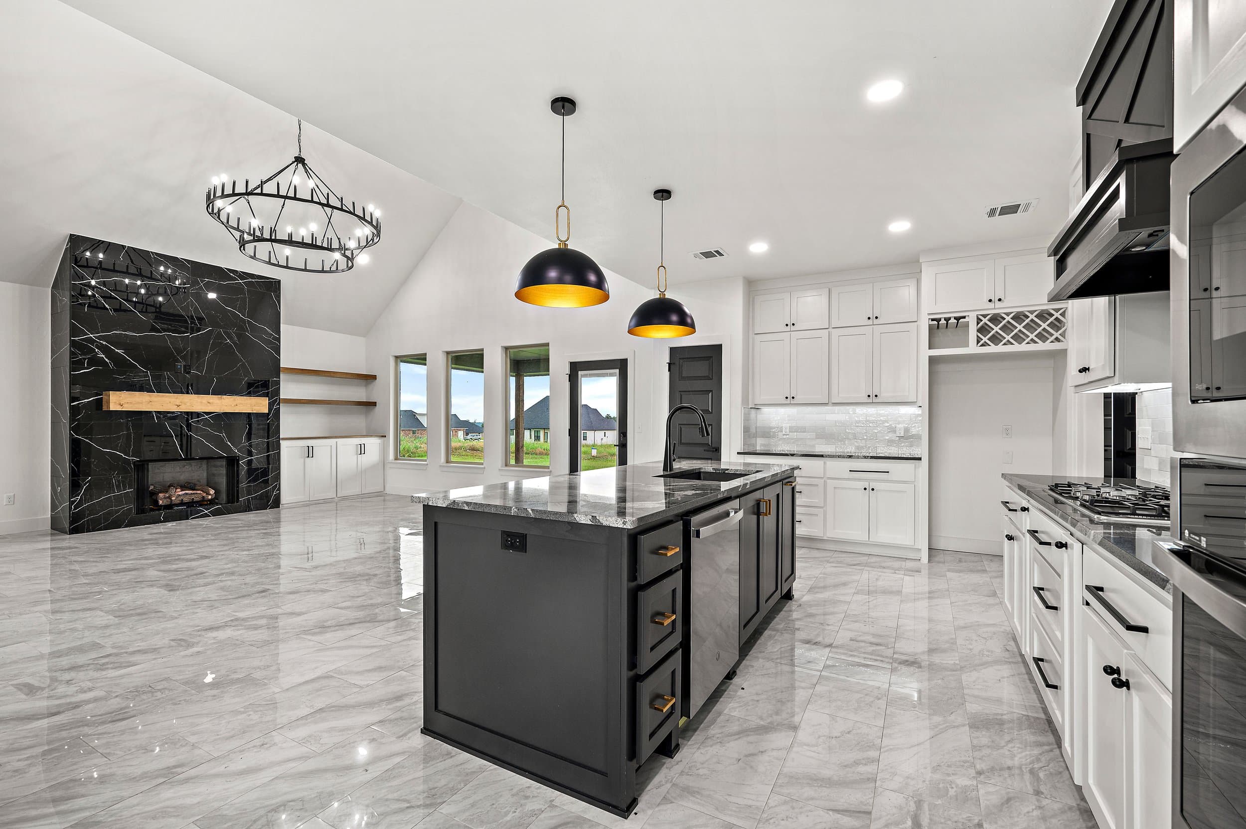 Open-plan kitchen with a black island, marble floors and a vaulted ceiling