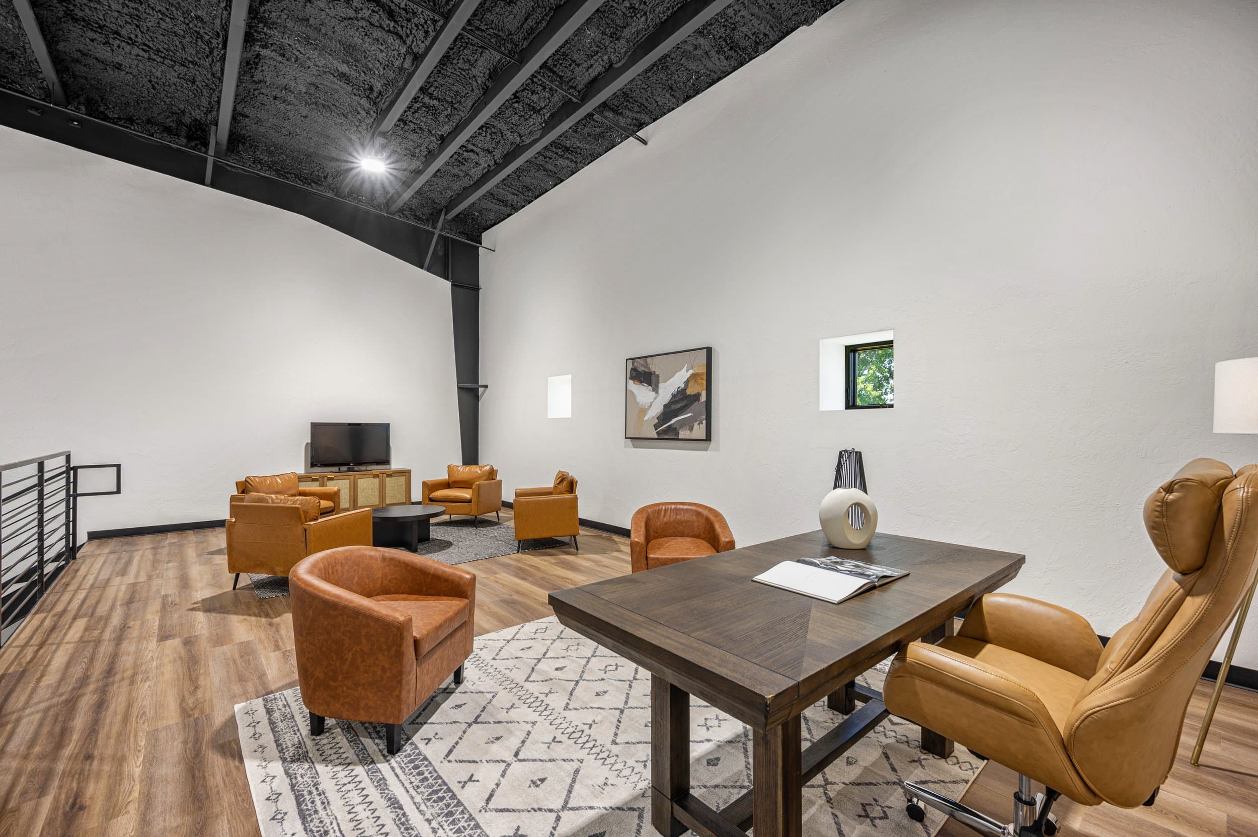 Office lounge with leather armchairs beneath an exposed industrial ceiling