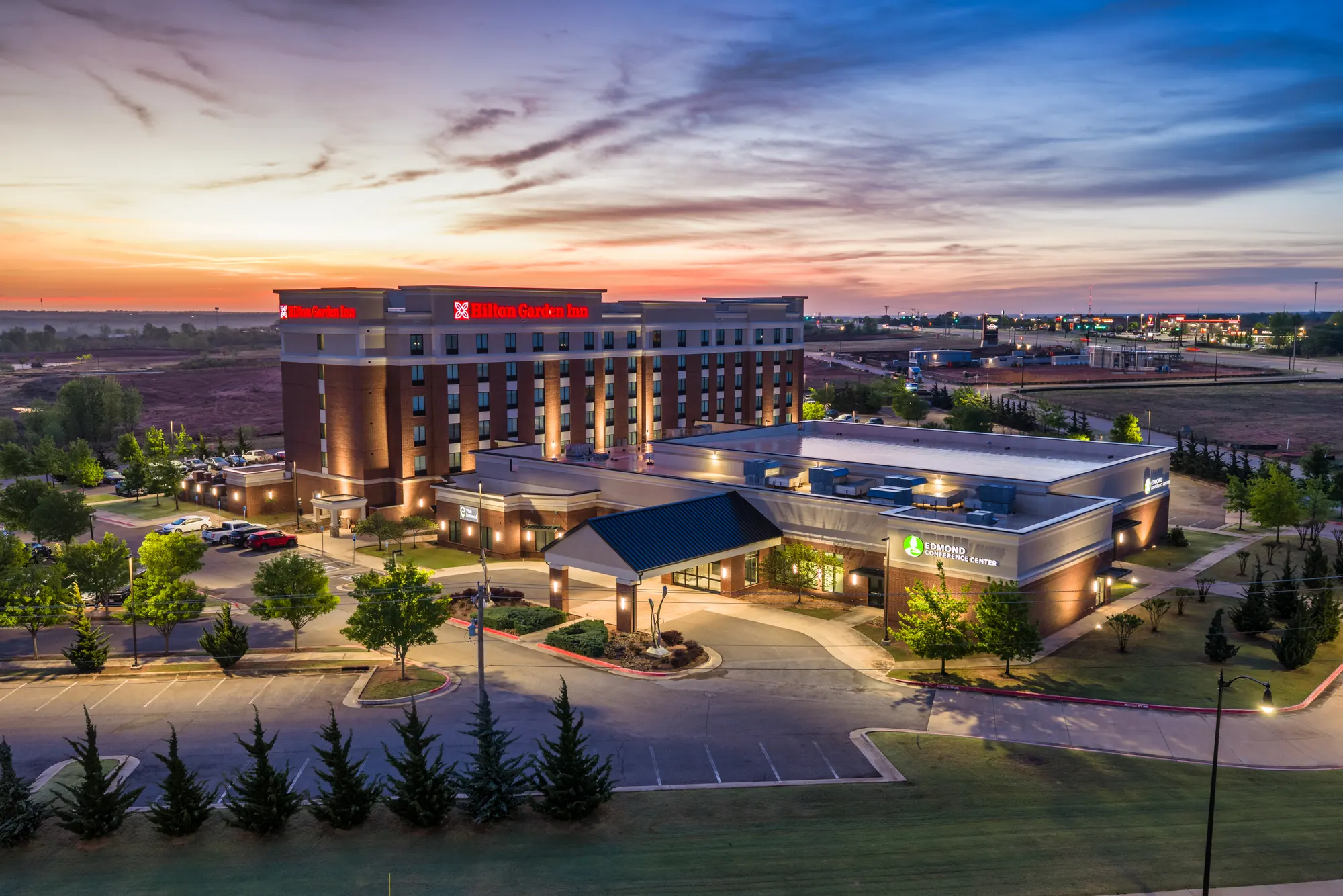 Aerial view of a Hilton Garden Inn and its forecourt at dusk
