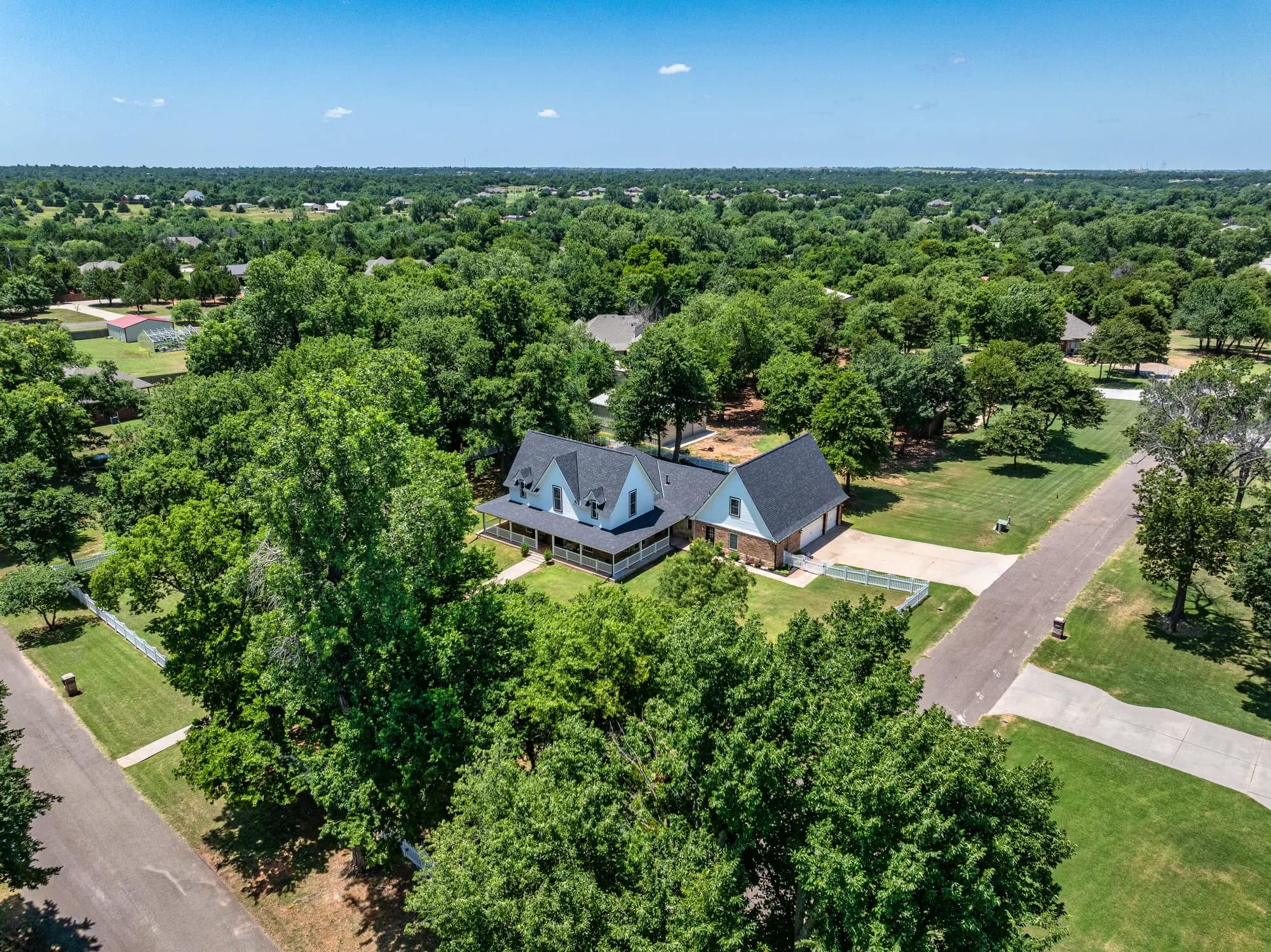 Aerial view of a homestead tucked into mature trees near Blanchard
