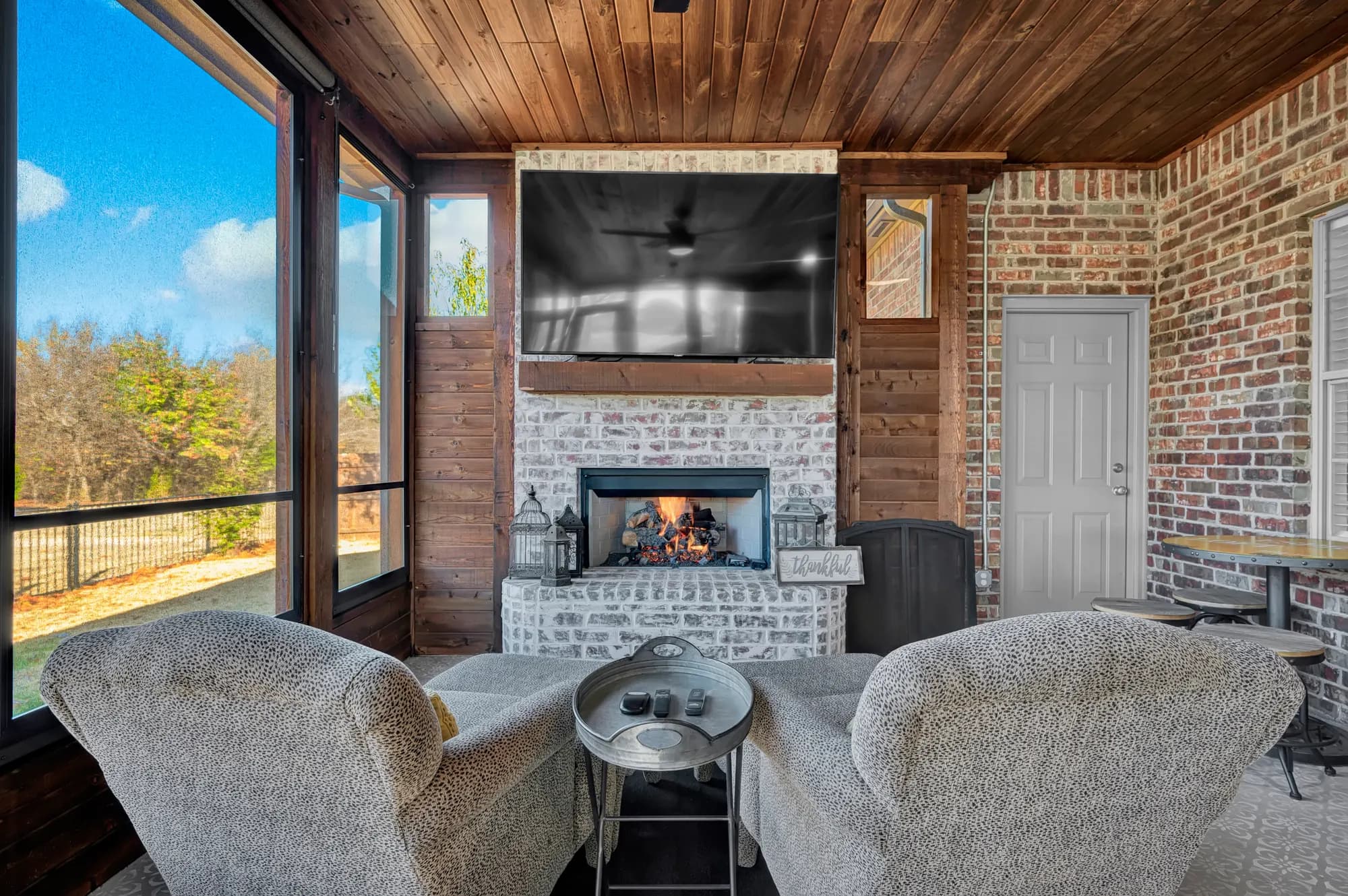 Sunroom with a brick fireplace, cedar ceiling and wraparound windows