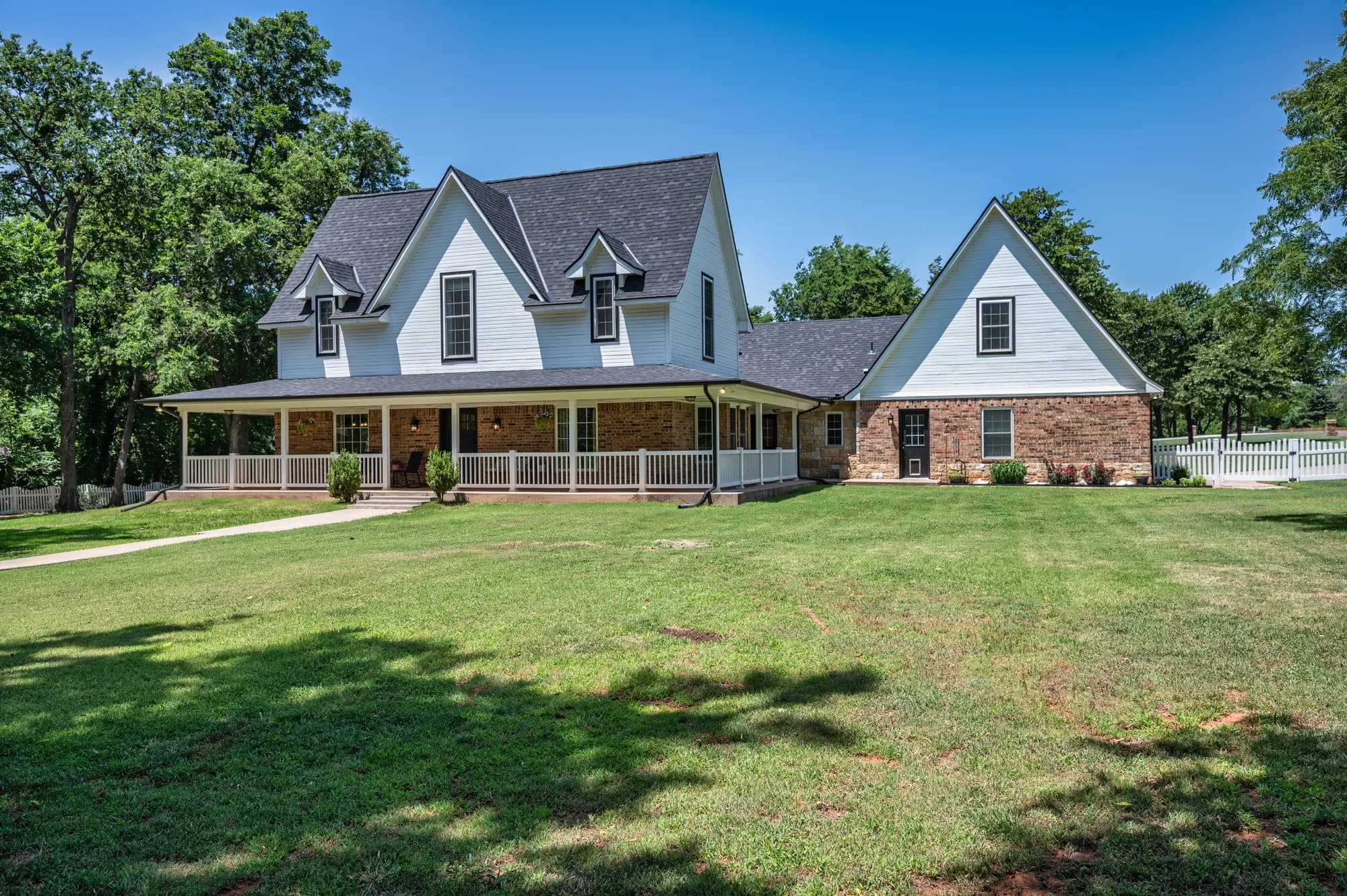 White farmhouse with a wraparound porch and dormer windows
