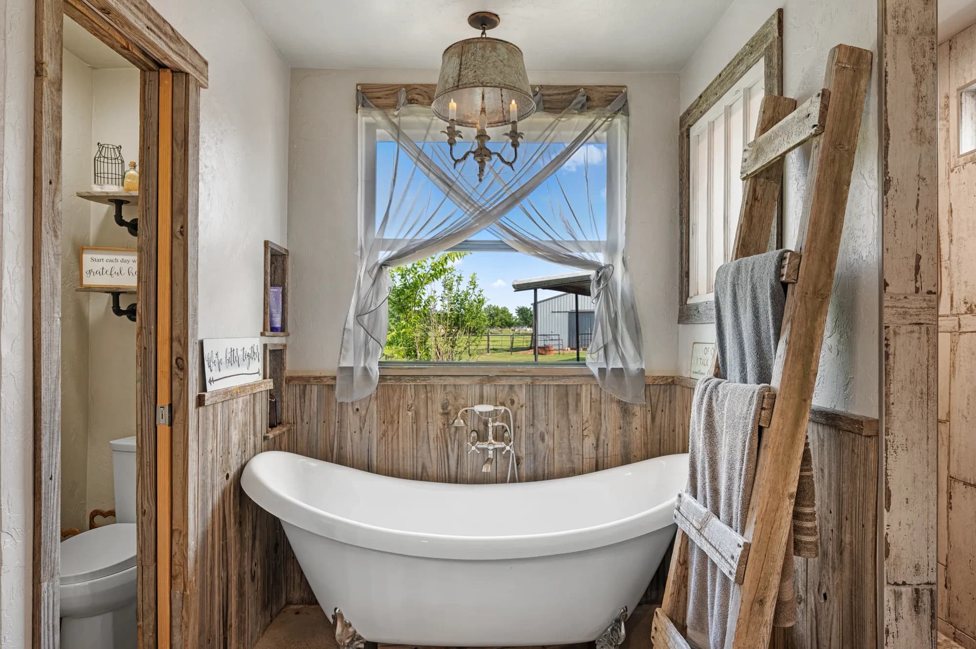 Farmhouse bathroom with a clawfoot tub framed by barn wood