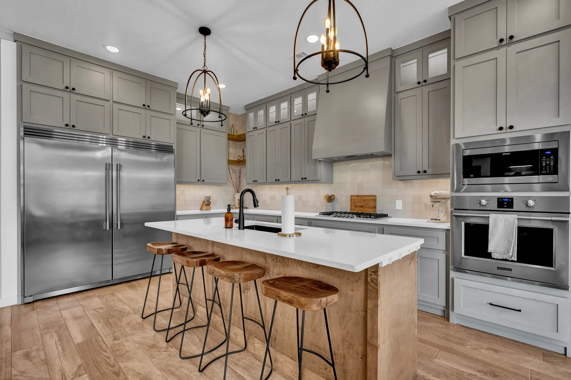 Grey shaker kitchen with a butcher-block island and lantern pendants