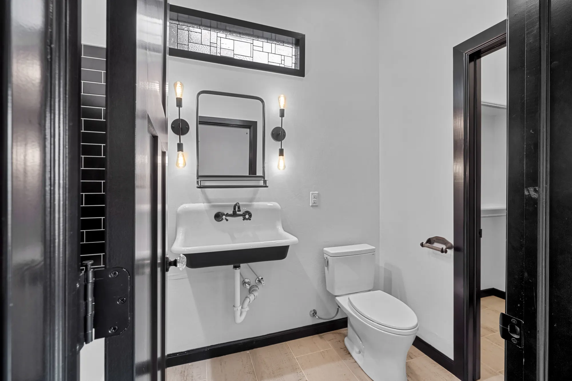 Powder room with a trough sink, transom window and black trim