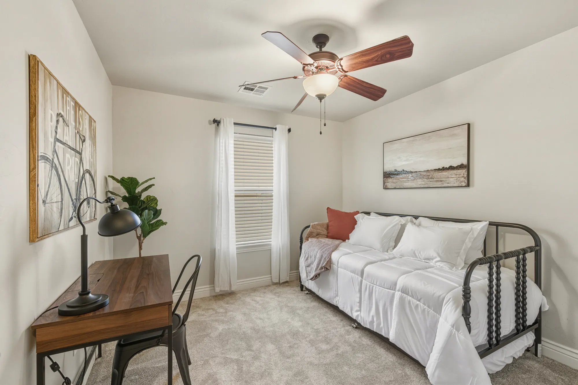 Guest room styled with an iron daybed and a compact writing desk