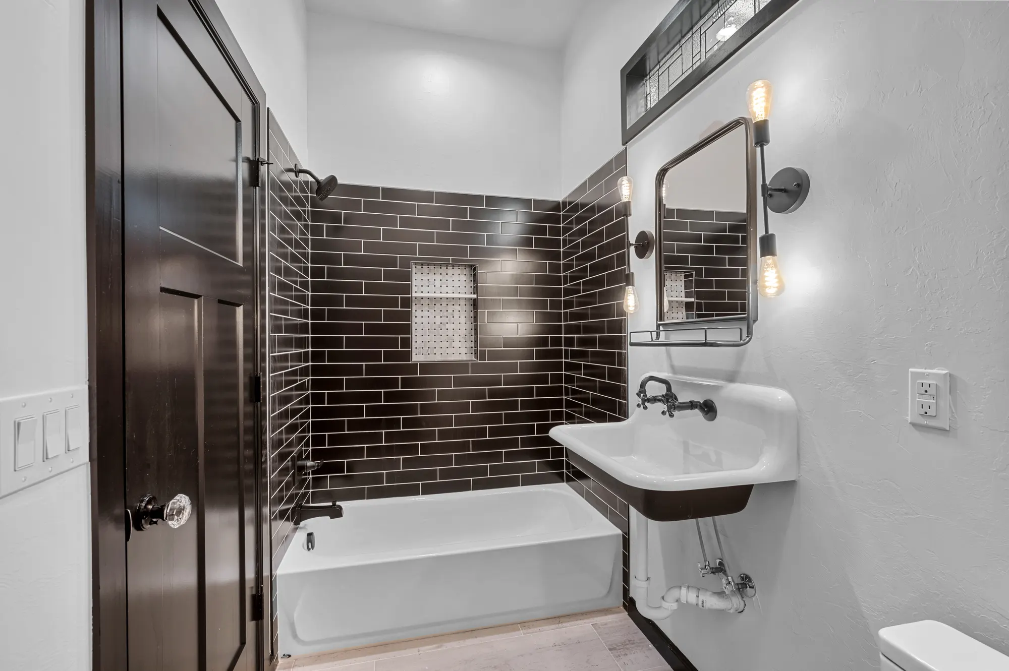 Bathroom with charcoal subway tile, a shower niche and a wall-mount faucet