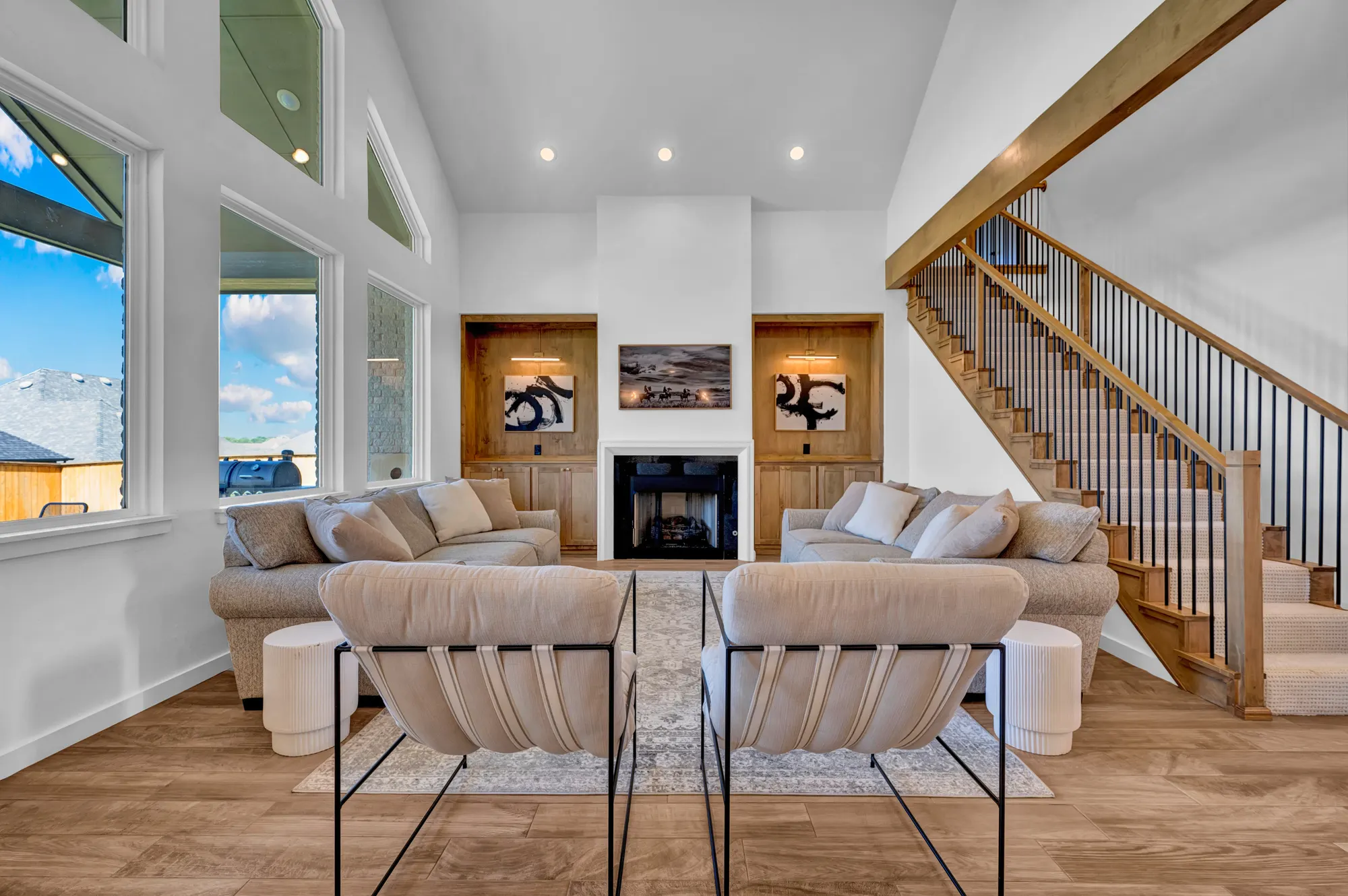 Bright living room with a vaulted ceiling, linear fireplace and open staircase