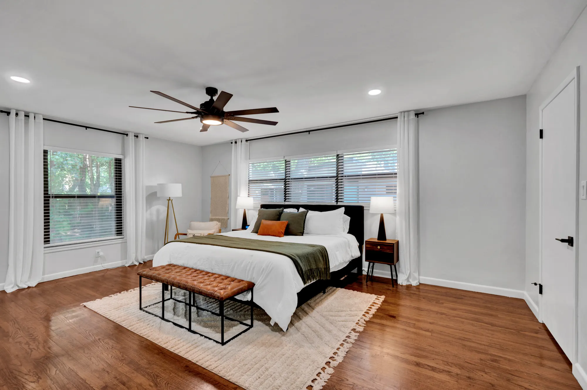 Primary guest bedroom with a leather bench and woven rug