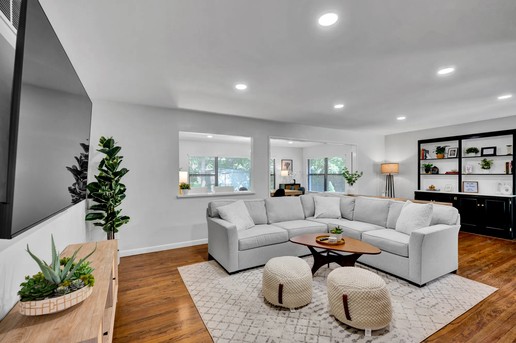 Norman rental living room with a pale sectional, poufs and warm wood floors