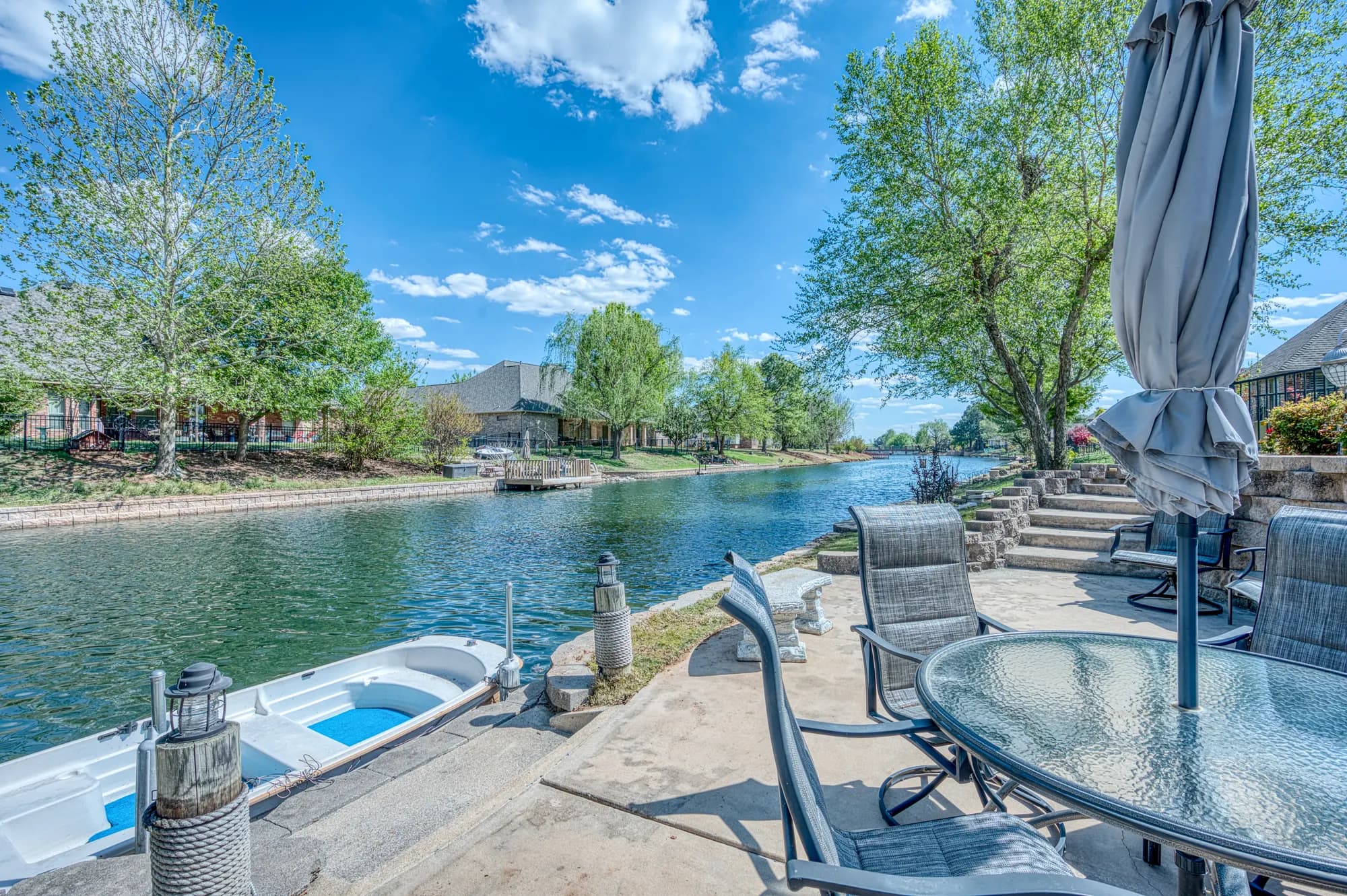 Waterfront patio with a boat dock, umbrellas and canal views
